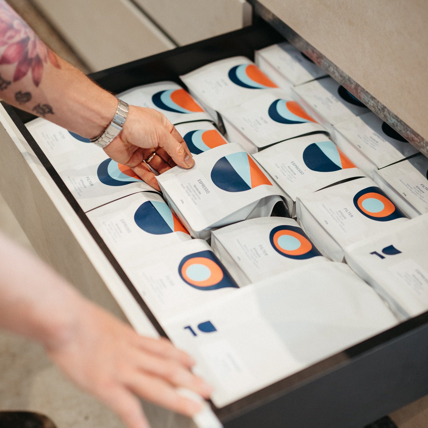 Person reaching into a drawer filled with neatly arranged boxes.